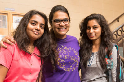 Group of international female students smiling on stairs.